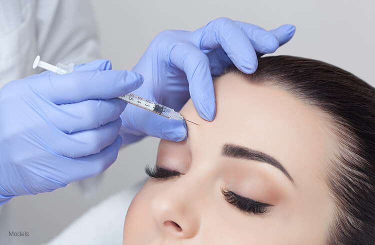 A woman receiving BOTOX® Cosmetic to smooth frown lines between the brows and slow them down from becoming permanent.