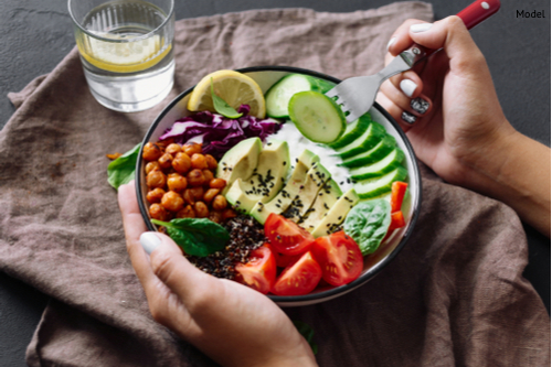 A woman eating a salad filled with omega-3 fatty acids as part of the anti-aging diet.