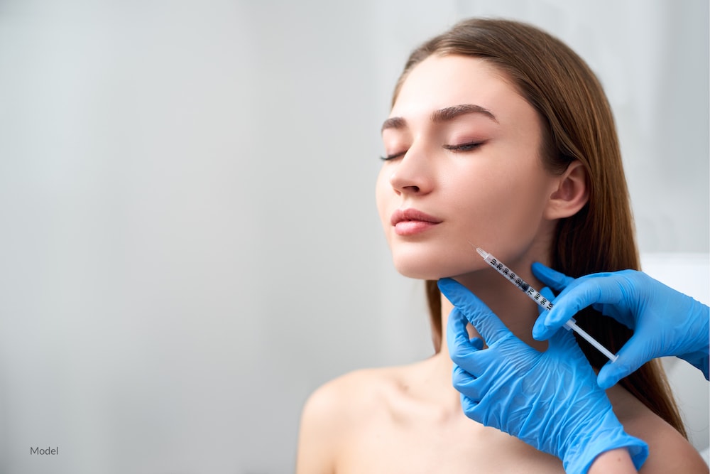 Woman getting a dermal filler injection in her lower face.